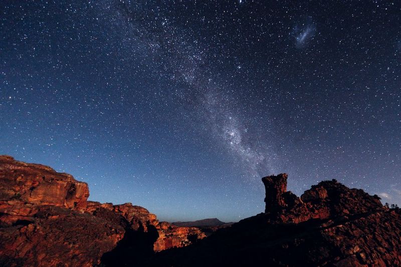 Craggy orange rock formations silhouetted against a starry night sky.