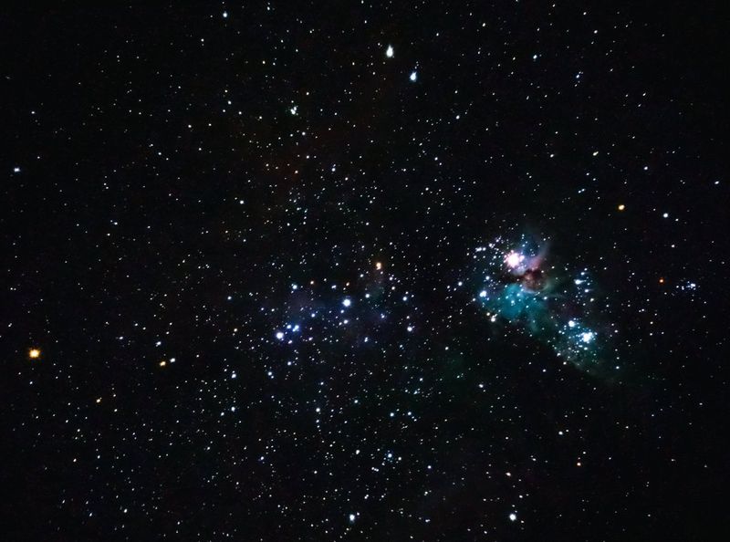 A field of stars with a prominent nebula on the right.