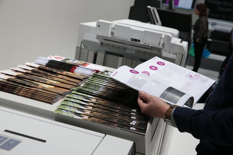 Work professional reviewing booklets printed, folded and stapled on Canon imagePRESS printer and finisher