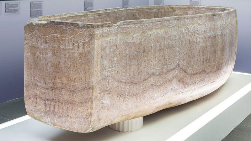 A high-resolution facsimile of an ancient Egyptian sarcophagus displayed on a white platform.
