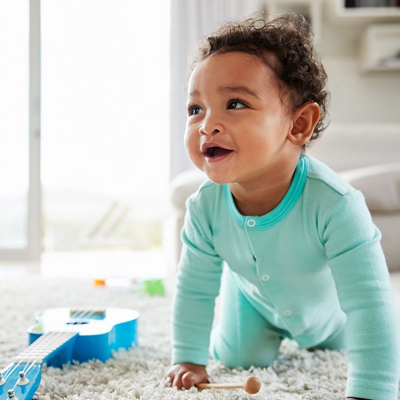 A baby crawls on a rug.