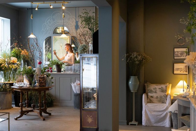 Dame står midt I rommet og jobber med blomster