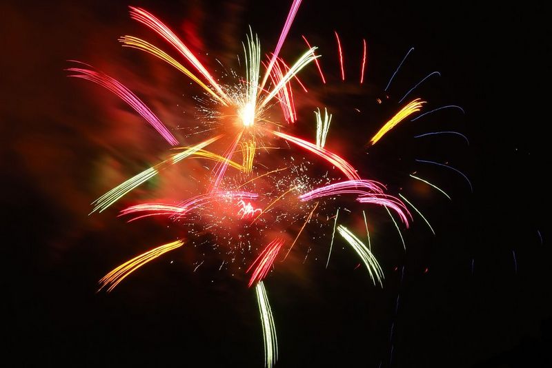 Multicoloured fireworks explode in the night sky.