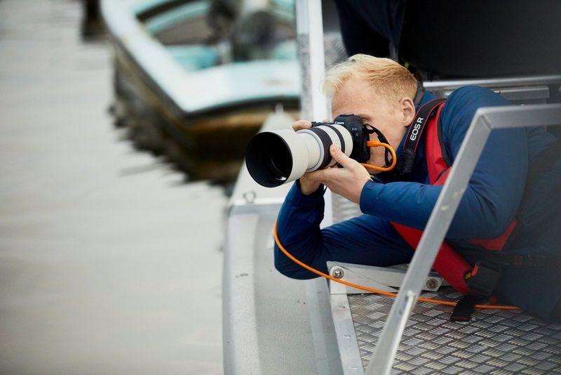 Il fotografo Matthew Joseph sdraiato su un fianco vicino all'acqua mentre scatta con una fotocamera Canon EOS R e un obiettivo Canon RF 70-200mm F2.8 L IS USM.