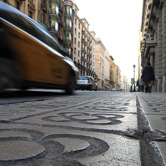 Street-level shot shows a car passing pedestrians.