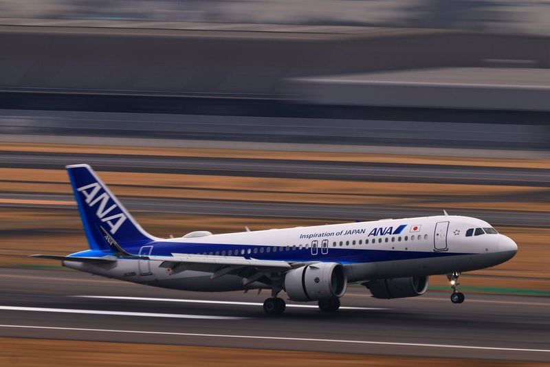 Un avion décolle au crépuscule, l'arrière-plan de l'aéroport est flou en raison du panoramique de la caméra.
