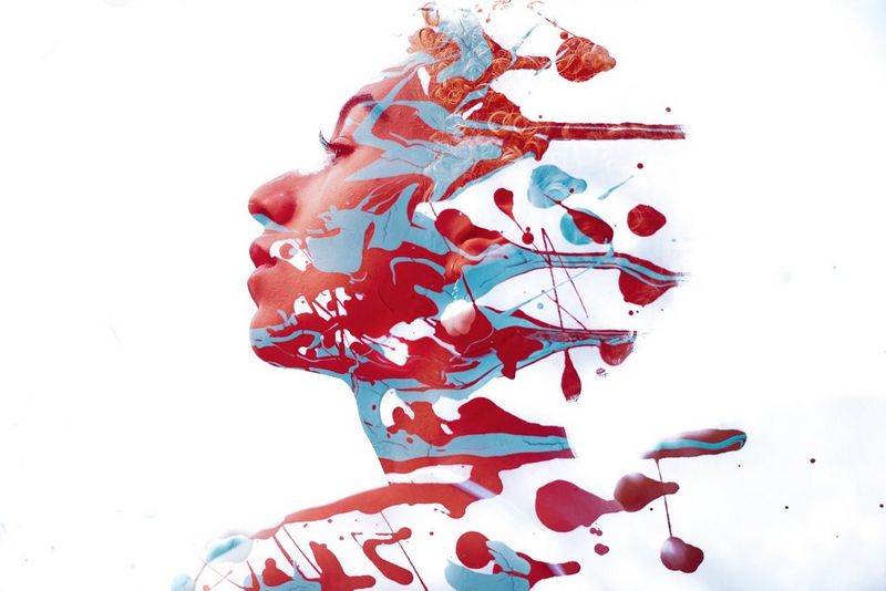The outline of a woman's face and shoulders are filled in with swirling red and blue paints.