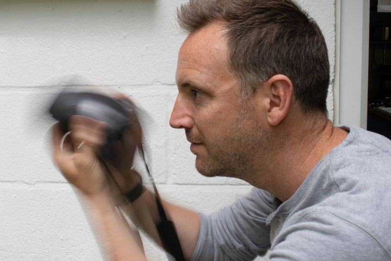 Мужчина быстро наклоняет камеру Canon вверх и вниз.