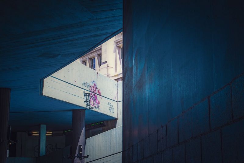 A street photography shot taken in an underpass, with light peeking through onto a graffitied wall.