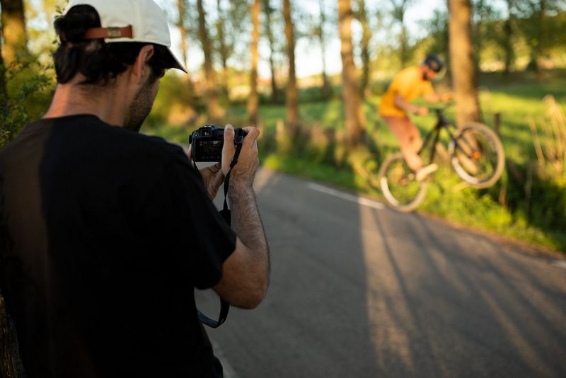 Canonov ambasador Jean-Baptiste Liautard s fotoaparatom Canon EOS RP fotografira kolesarja, ki na gorskem kolesu izvaja trike na podeželski stezi.