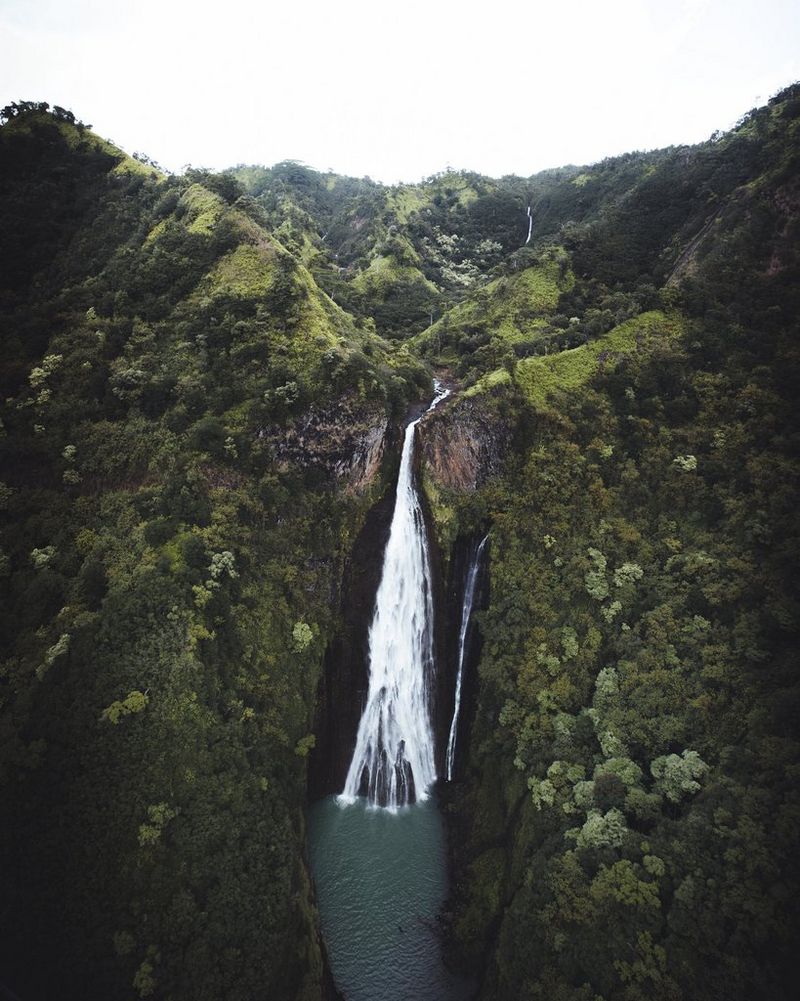 Zeleni planinski lanac s vodopadom u sredini.