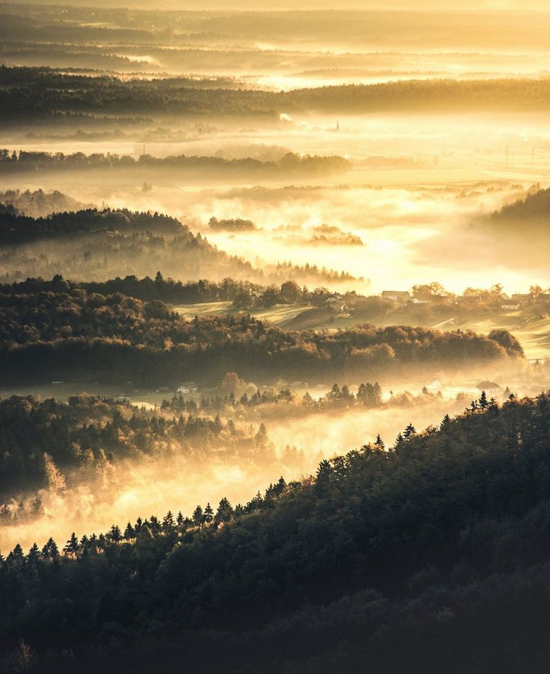 Nevel vult de valleien tussen met bomen bedekte bergen. Het contrast is verhoogd en er is een warme tint toegevoegd om het herfstgevoel te versterken.