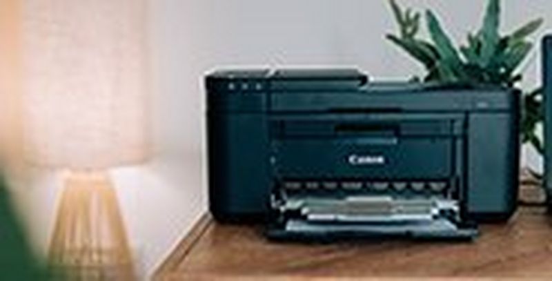 A Canon PIXMA printer on a desk in a home office.