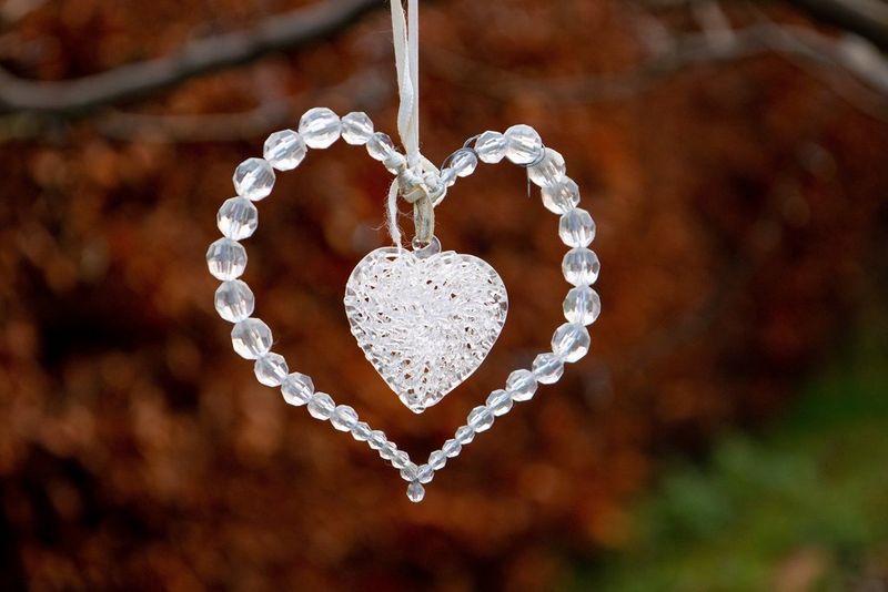 Садовое украшение в форме сердца из стеклянных бусин на размытом фоне.