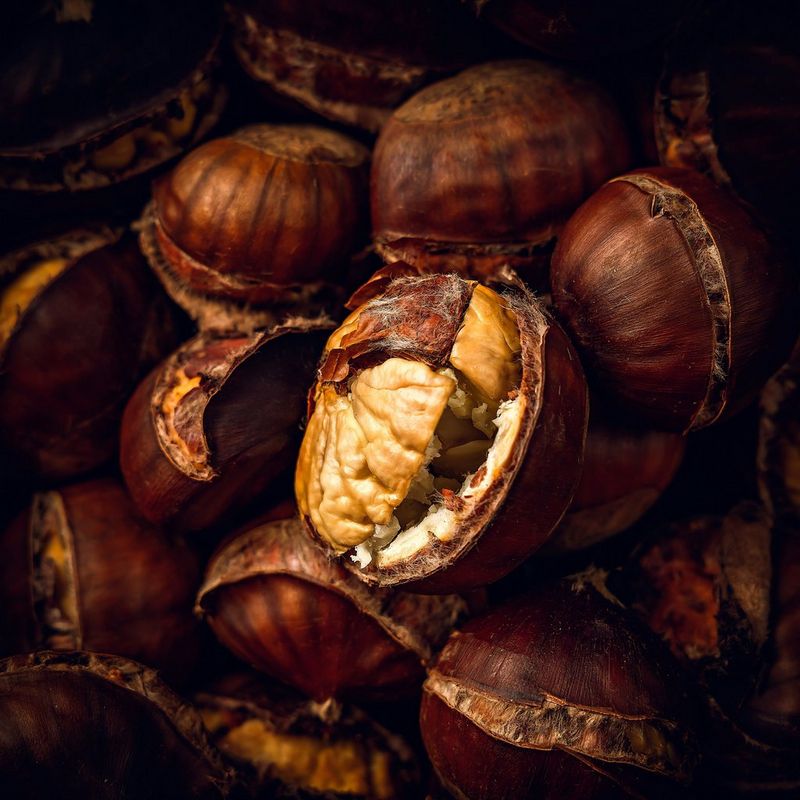 A close-up shot of some roasted chestnuts, with one bursting out of its shell.