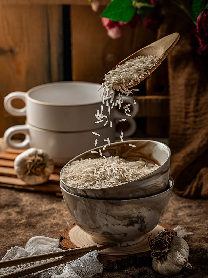 A stack of bowls being filled with rice, being poured from a wooden spoon floating above them. 