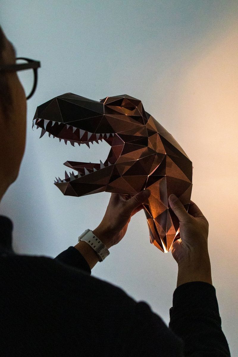 A person installs an assembled Canon Creative Park dinosaur night light on a wall.