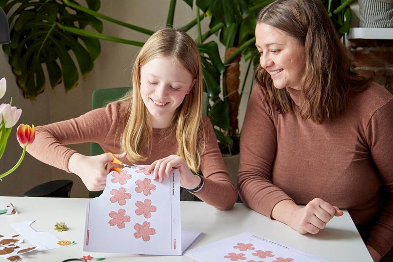  Designer Hannah Bullivant sits next to a young girl who is cutting out flower templates downloaded from Canon Creative Park.
