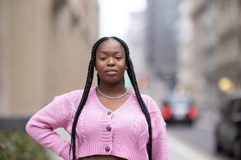 דיוקן של אישה עם צמות ארוכות לבושה בעליונית ורודה.