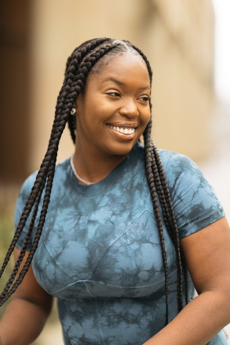 אישה עם צמות ארוכות לובשת חולצת באטיק כחולה.