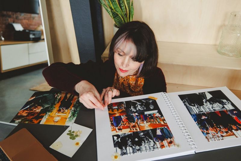 A woman adds a decorative corner to a montage of pictures in a homemade wedding album.