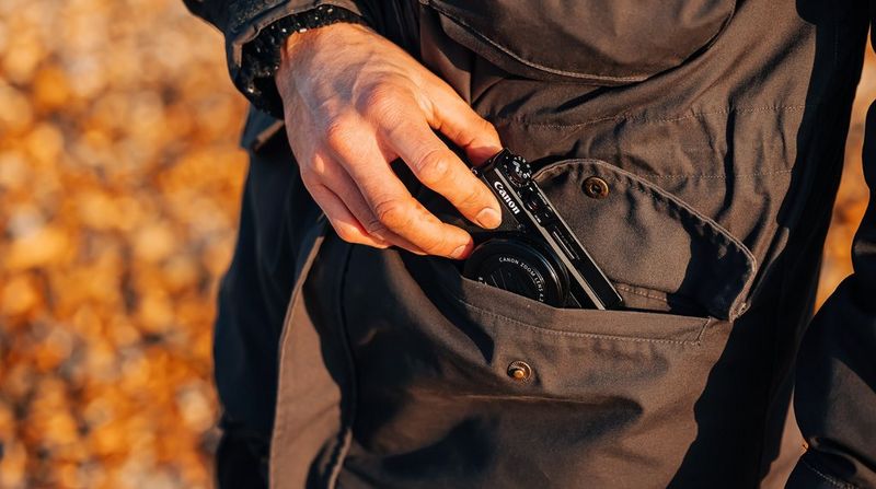 Een man haalt een Canon PowerShot G7 X Mark III-camera uit zijn jaszak.