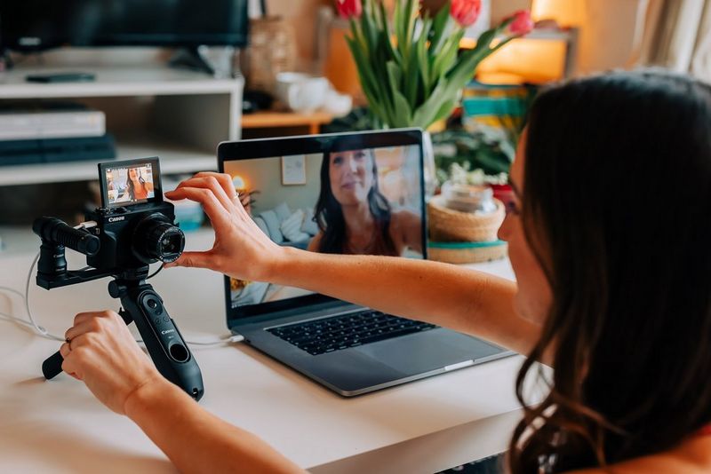 Een vrouw zet haar Canon PowerShot G7 X Mark III naast haar laptop om een yogales te livestreamen.