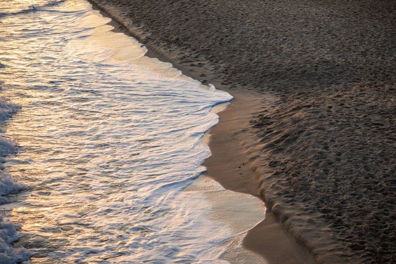 Kabbelend zeeschuim op een zandstrand in de schemering.