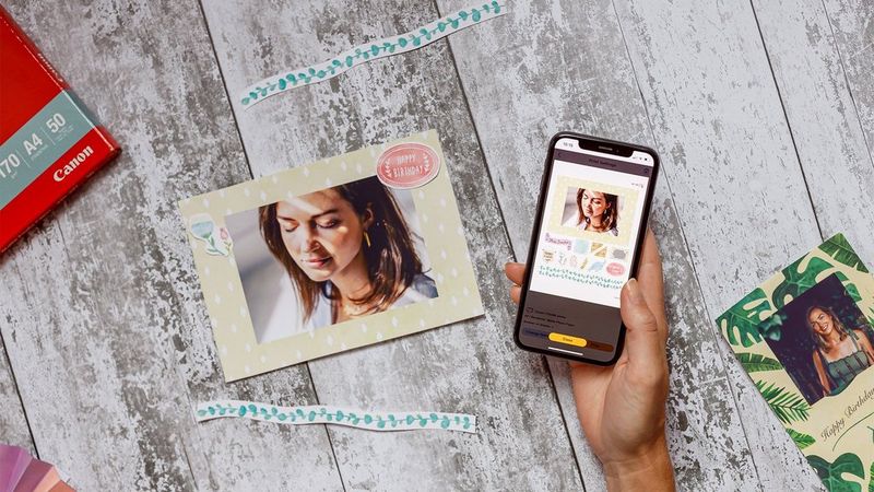 A hand holding a smartphone displaying the Creative Park app. A personalised card is on the table. 