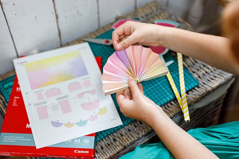 A girl folds a paper party garland printed from the Creative Park app.