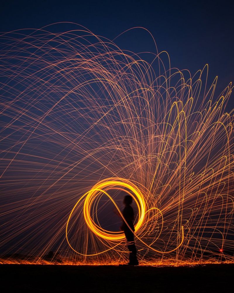 O expunere prelungită a unei siluete lângă un cerc de lumină aurie. Dâre de lumină radiază din conturul cercului.