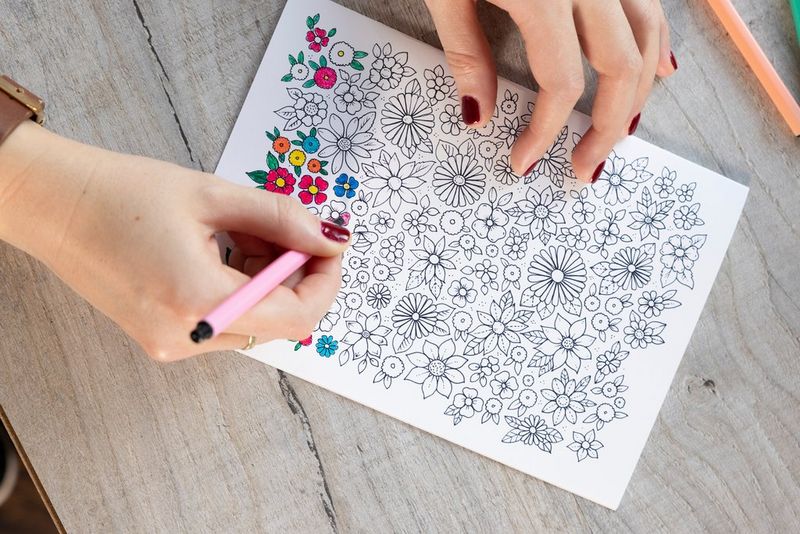 A colouring page with flower design being coloured in with pink marker.