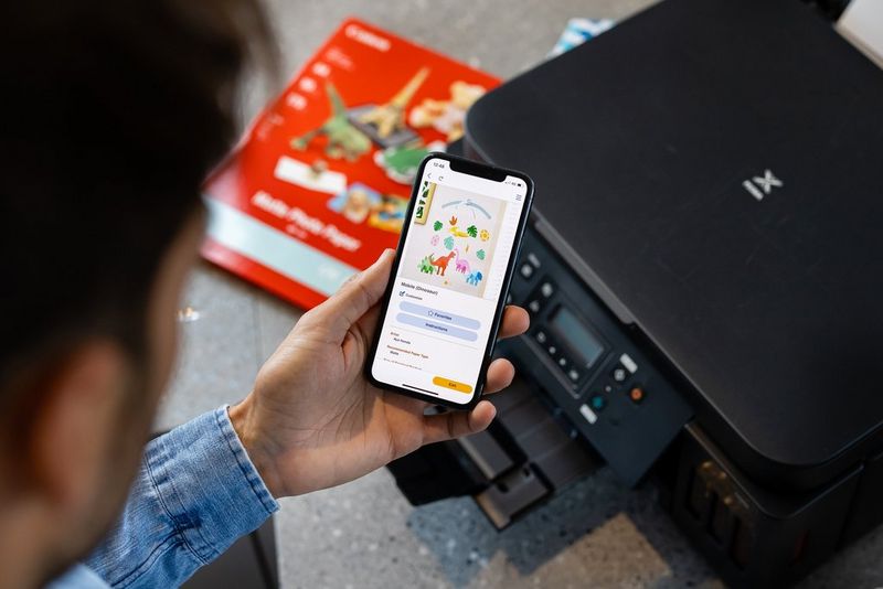 Мужчина использует телефон для беспроводной печати на принтере PIXMA G6040.