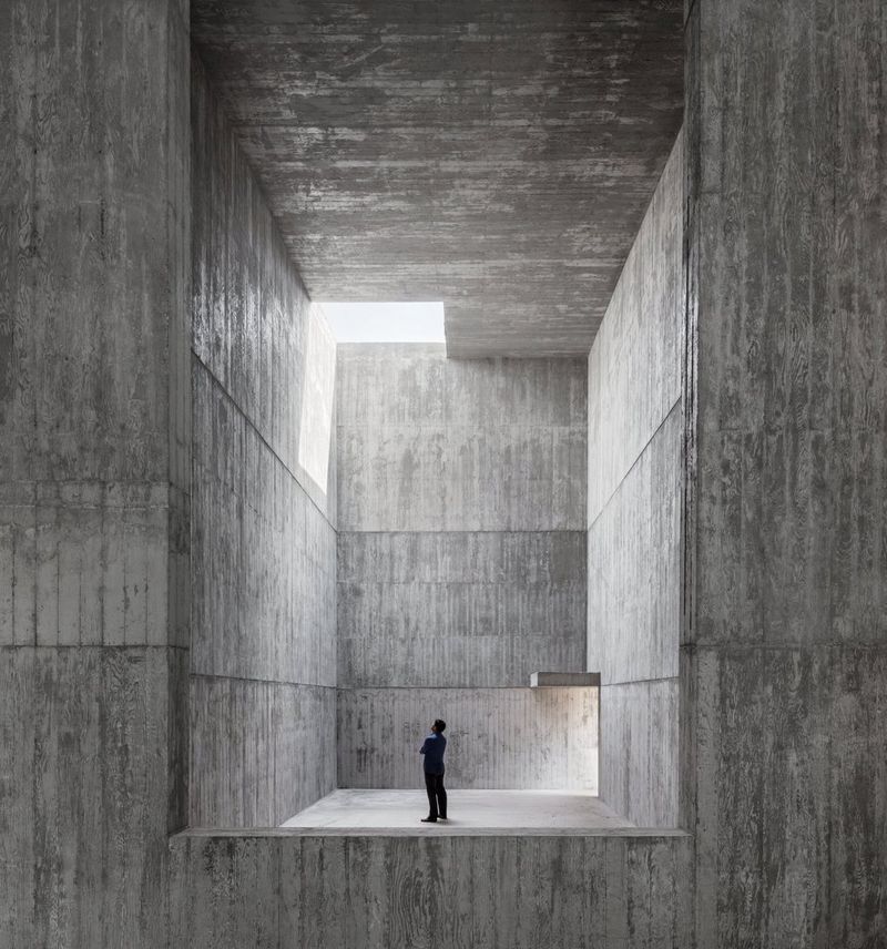 A figure stands within a large grey geometric structure.