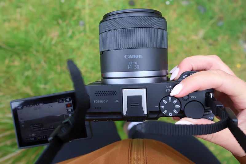 Prst vlogerke Niam Mekinon dodiruje točkić za izbor režima sa gornje strane fotoaparata Canon EOS R50 V dok snima vlog video.