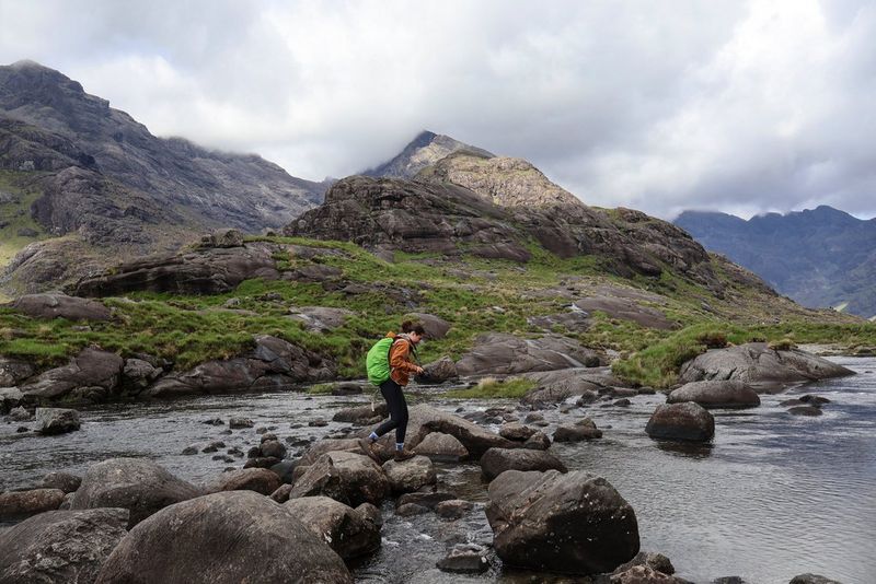 Vlogerka Niam Mekinon probija se preko kamenja u potoku na ostrvu Skaj, dok nosi fotoaparat Canon EOS R50 V.