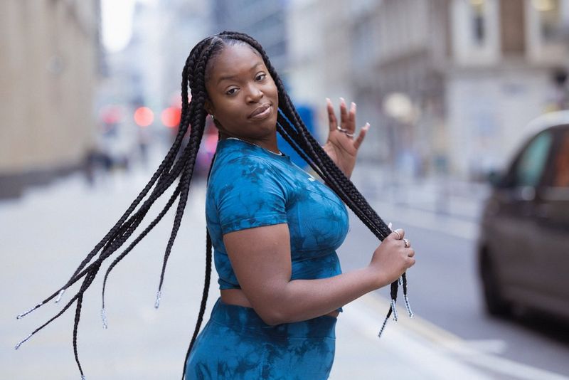 אישה בתלבושת כחולה בצבעי בטיק (Tie-dye) מעיפה לאחור את צמותיה הארוכות.