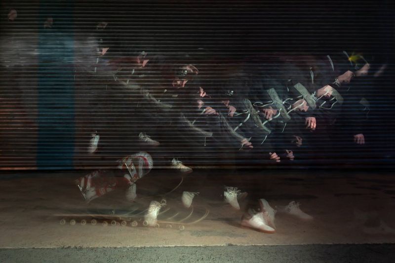 Un'esposizione lunga realizzata con un flash a impulsi di uno skateboarder che esegue un trick.