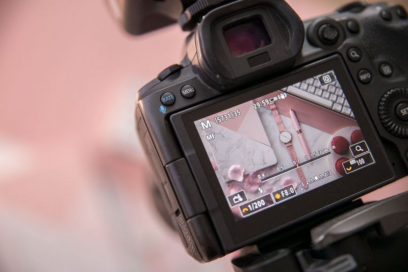 Het LCD-scherm van een Canon-camera met daarop een flatlay-foto van een roze horloge en bijpassende roze en witte props.