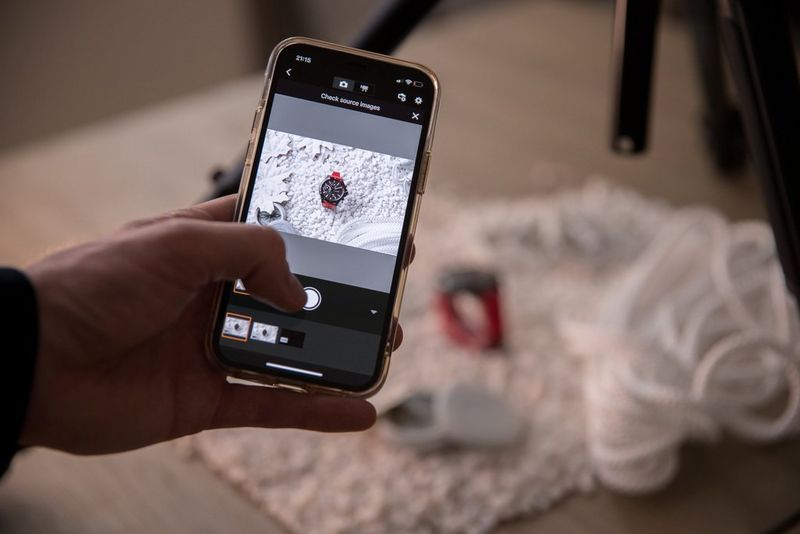 Een fotograaf die de Canon Camera Connect-app op een smartphone gebruikt om een foto te maken van een rood horloge, omgeven door klimuitrusting.