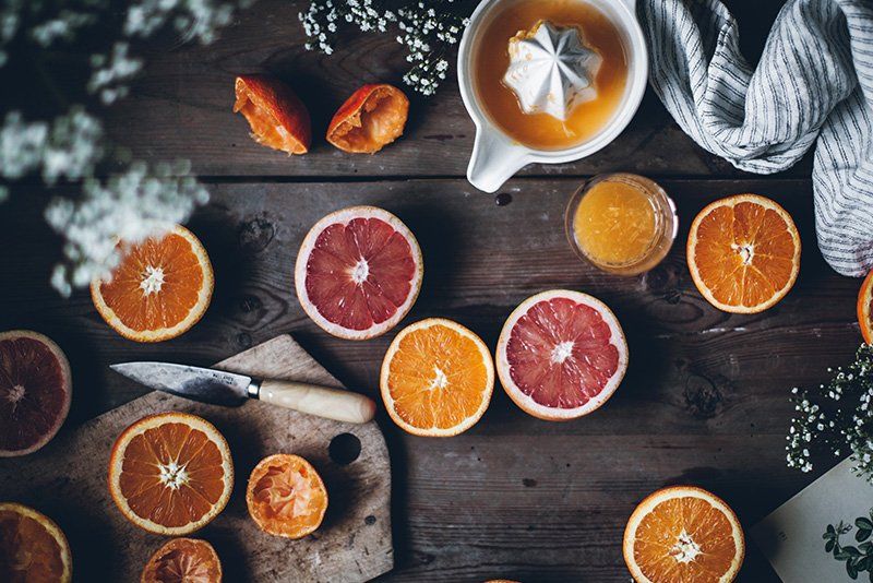 A citrus table display with multiple oranges sliced in half, with a chopping board and a lemon squeezer. 