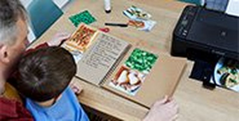 A father and son flick through the pages of a homemade recipe book.