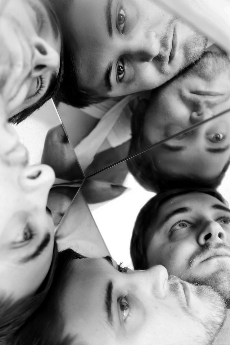 Črno-bel posnetek več slik istega obraza v zrcalu.