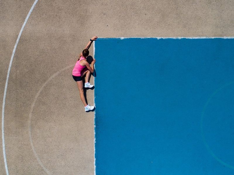 Posnetek od zgoraj, na katerem ženska v športnih oblačilih navidezno pleza na modri blok.