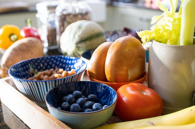 Groente, fruit en brood in kommetjes op een dienblad.