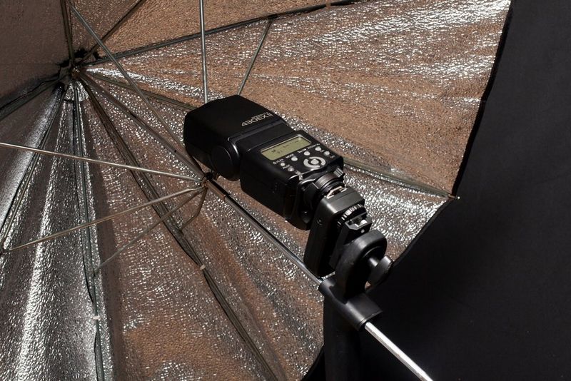 Bližnji posnetek srebrnega dežnika in bliskavica Speedlite.