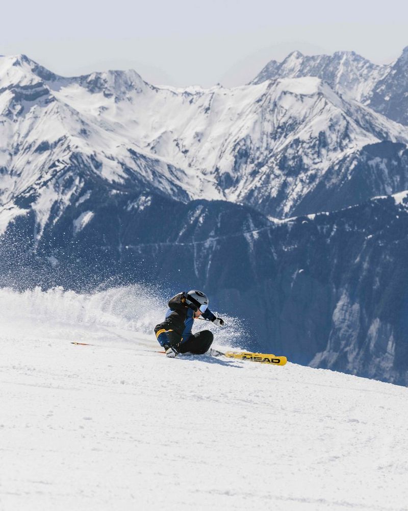 A person skis down a mountain, snow spraying out behind them, in a photo taken on a Canon EOS R5 by Chris Priestley.