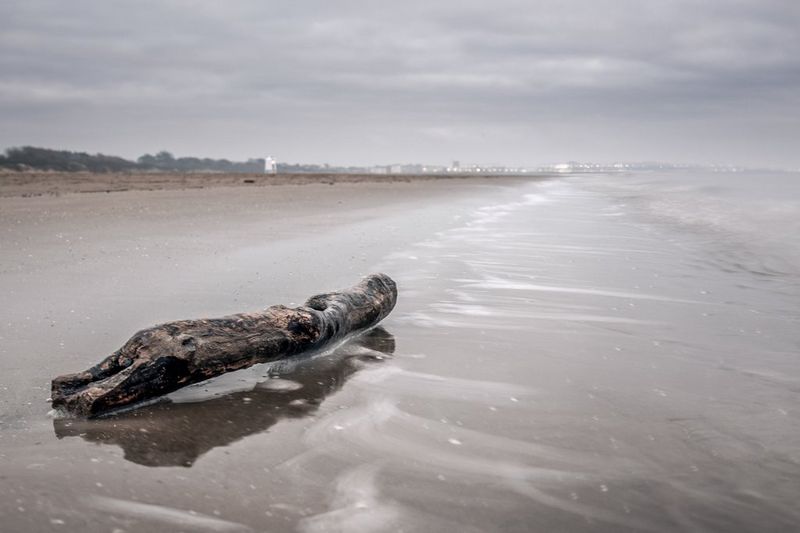 A piece of driftwood on a deserted shoreline. The movement of the waves has been blurred by the long exposure.