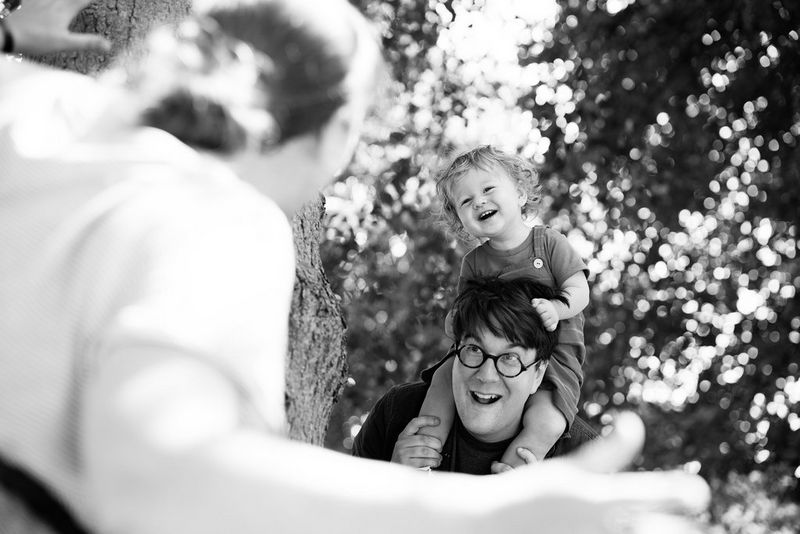 Черно-белый снимок маленького ребенка, сидящего на плечах своего отца.