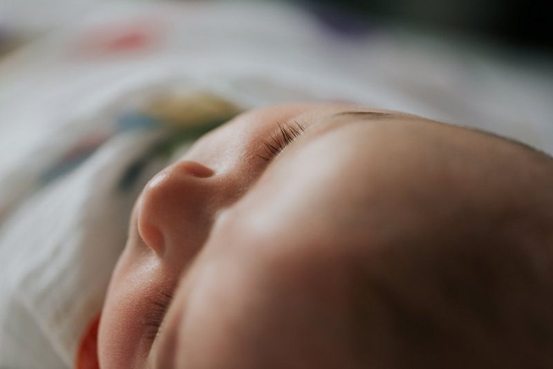 Un primo piano della testa di un bambino sdraiato sulla schiena.